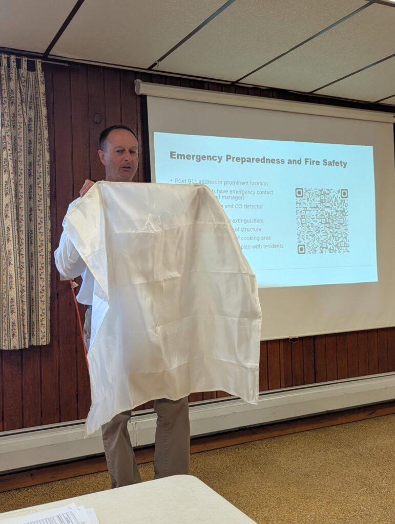 Jay Conizier demonstrating a fire blanket in front of a classroom.